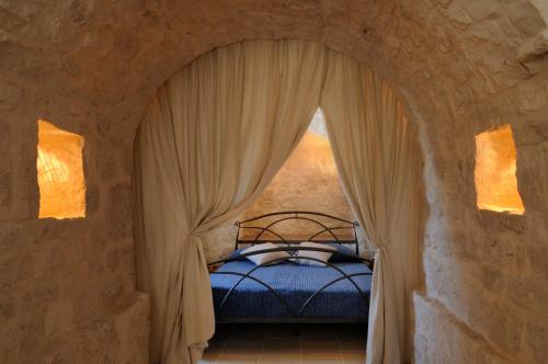 a bedroom with a bed in a stone wall at Il Borgo Delle Querce Villa Fichi Piscina privata in Martina Franca