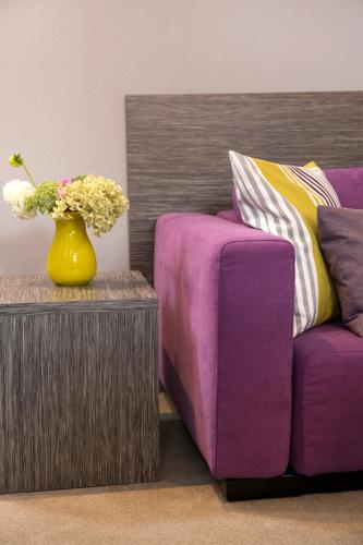 a vase of flowers on a table next to a couch at Hotel am Markt in Baden-Baden