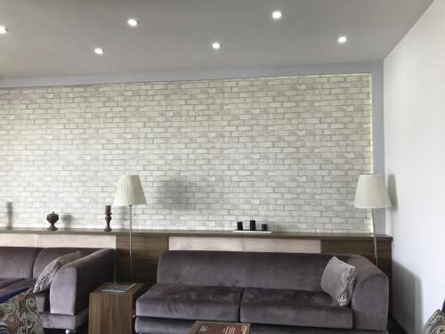 a living room with a couch and a brick wall at Hande Hotel in Mustafakemalpaşa