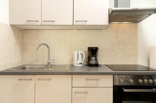 a kitchen with white cabinets and a sink at Dubravka apartmani in Mokošica
