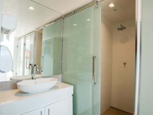 uma casa de banho com um lavatório e uma cabina de duche em vidro. em Copacabana Mar Hotel no Rio de Janeiro