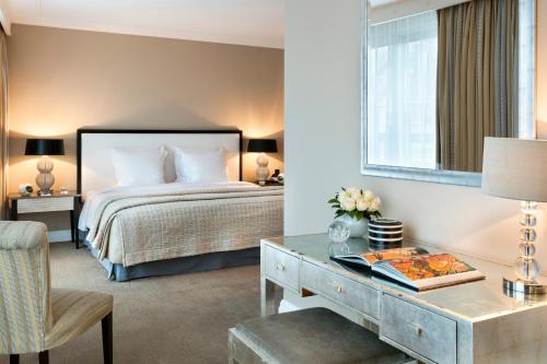 パリにあるワーウィック パリ （旧 ワーウィック シャンゼリゼ）のベッドとデスクが備わるホテルルームです。