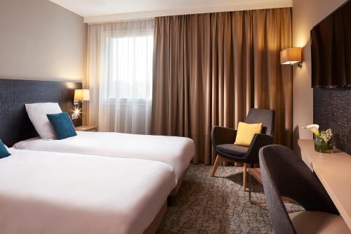 une chambre d'hôtel avec deux lits et une chaise dans l'établissement Mercure Colmar Centre Unterlinden, à Colmar