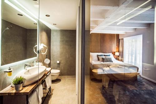 uma casa de banho com um lavatório e uma cama num quarto em Nomad Luxury Suites em Belgrado