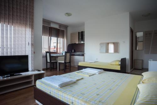 a room with a bed and a tv and a kitchen at Guest House Georgievi in Primorsko