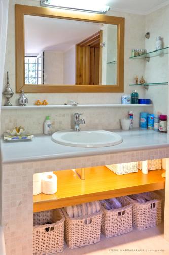 a bathroom with a sink and a mirror and baskets at Villa Mos in Kalamata