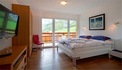 Schlafzimmer mit einem Bett, einem TV und einem Balkon in der Unterkunft Residenz Ambassador B11 in Leukerbad