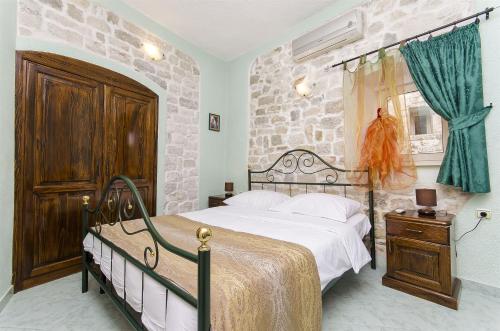 ein Schlafzimmer mit einem Bett und einer Steinmauer in der Unterkunft Palace Derossi in Trogir