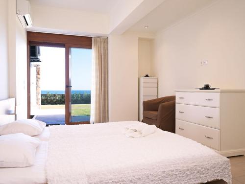 a white bedroom with a bed and a window at Luxury Villa Verna in Líndos