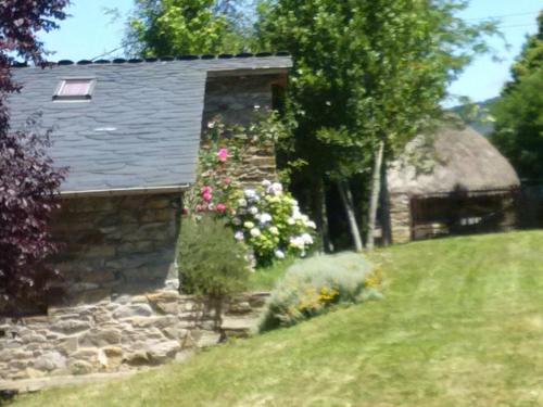 a stone house with flowers on the side of it at Casa dos Pedrouzos in Doncos