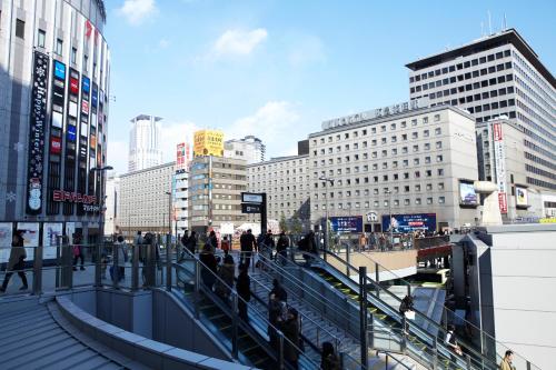 a group of people walking down a street in a city at Hotel New Hankyu Osaka in Osaka