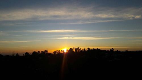 a sunset over a field with trees in the foreground at Hostal Casa de Los Taitas in Salento