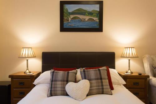 ein Schlafzimmer mit einem Bett mit zwei Lampen und einem Herzkissen in der Unterkunft Cedars Guest House in Aberdeen