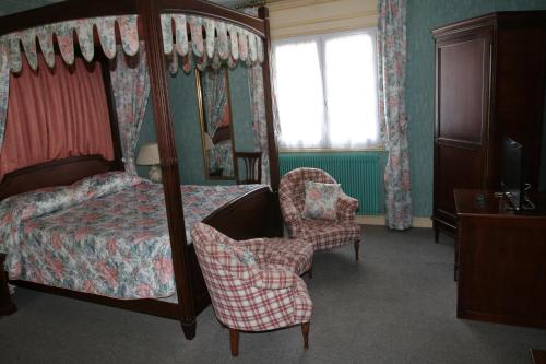 a bedroom with a canopy bed and a chair at Hotel Royal Albion in Mesnil-Val-Plage