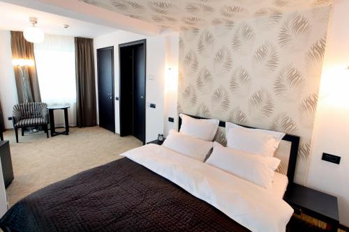 um quarto com uma cama grande e almofadas brancas em Ambiance Hotel em Bucareste