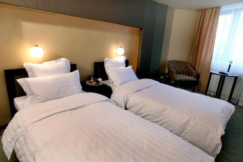 two beds in a hotel room with white pillows at Ambiance Hotel in Bucharest