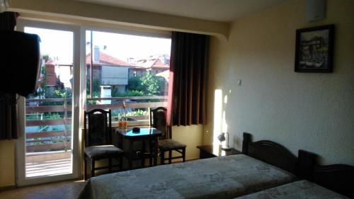 a bedroom with a bed and a table and a window at Hotel Tony in Nesebar