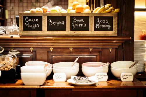 a counter with bowls and other food items on it at Swiss-Chalet Merlischachen - Romantik Schloss-Hotel am See in Küssnacht