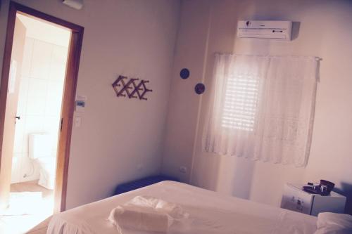 a white bedroom with a bed and a window at Guaiamu Suítes Ilhabela in Ilhabela