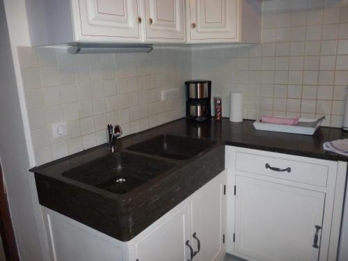 a kitchen with a black sink and white cabinets at Le Mazot in Villaroger