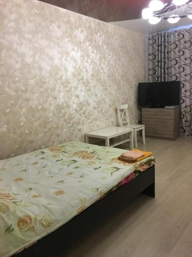 a bedroom with a bed and a flat screen tv at Apartment Ozernaya 7 in Tver