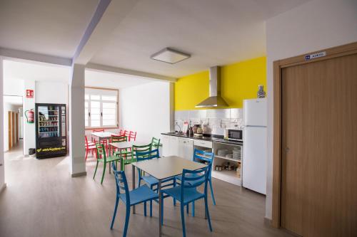 
a kitchen with a table and chairs and a refrigerator at Albergue As Pedreiras in Villalba
