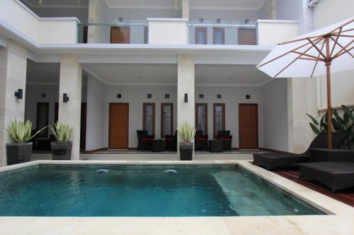 una piscina di fronte a una casa con ombrellone di Tom Guest House a Legian
