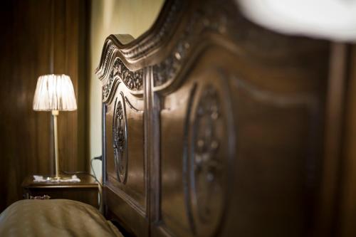 a large wooden bed in a room with a lamp at Residenza San Vito in Calamandrana
