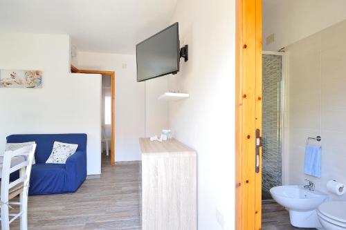 a bathroom with a blue couch and a tv on the wall at Apartment Dissoro in Santa Maria Navarrese