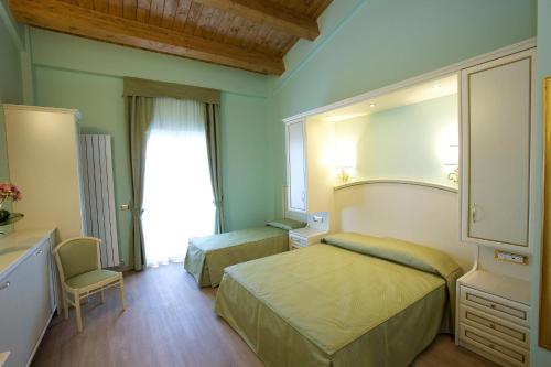 Pokój hotelowy z 2 łóżkami i lustrem w obiekcie Hotel Da Angelo w Asyżu