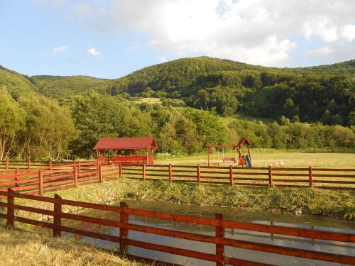 a red fence with a playground in a field at Halasto Pension in Praid