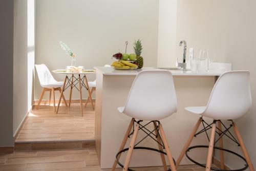 a kitchen with two white bar stools and a counter at Riaki Apts in Malia