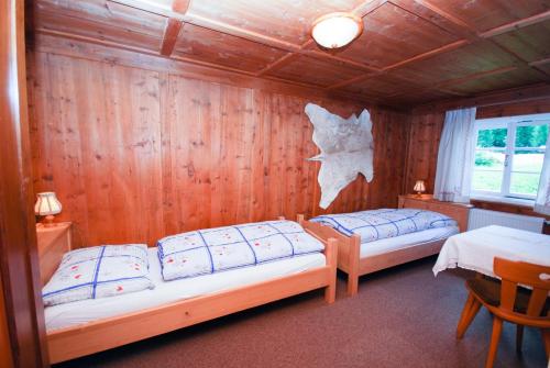 two beds in a room with wooden walls at Villgraterhof in Sesto