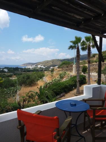 a balcony with chairs and a table and palm trees at Apaggio Apartments in Katapola