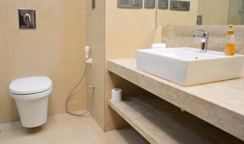 een badkamer met een witte wastafel en een toilet bij Hotel Grand Maple in Jaipur