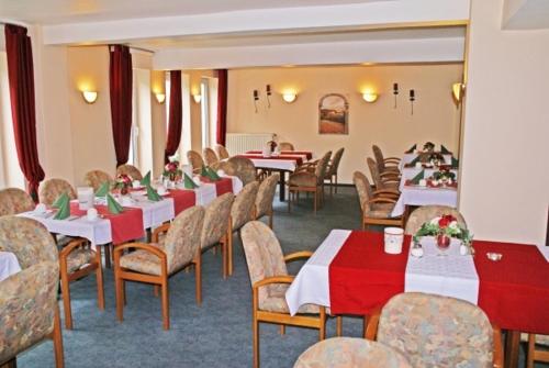 a dining room with red and white tables and chairs at Weser Wasserbetten Hotel Baxmann in Hessisch Oldendorf
