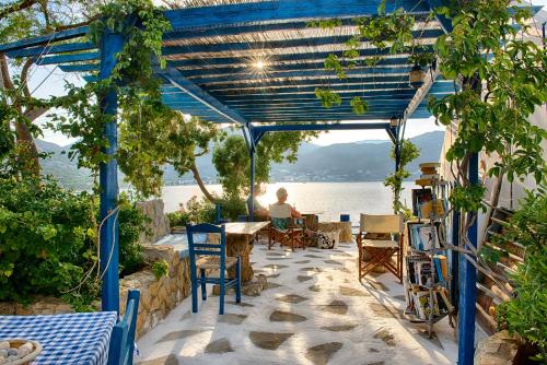 a woman sitting at a table under a blue pergola at Antoniadi Rooms in Livadia
