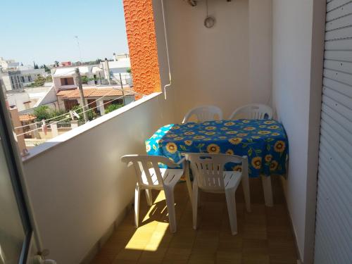 a small balcony with a table and chairs and a window at Monolocali Angelica in Porto Cesareo