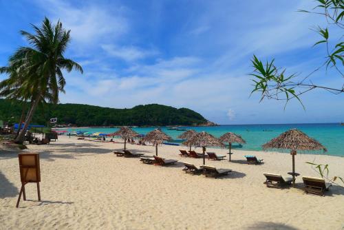 a beach with chairs and umbrellas and the ocean at BuBu Villa in Perhentian Island