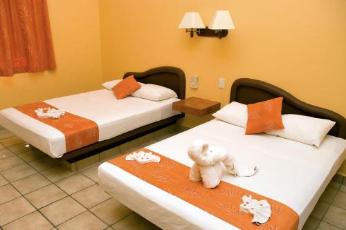 a room with two beds with a teddy bear sitting on them at Hotel LunaSol in Playa del Carmen