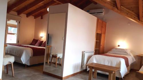 a bedroom with two beds and a mirror at Hotel Antiguos in San Martín de los Andes