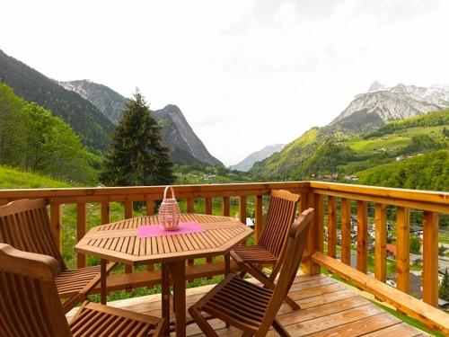 a table and chairs on a wooden deck with mountains at Bauernhof Wildfang in Dalaas