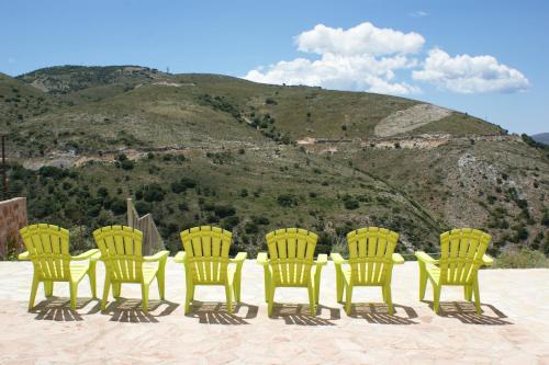 a group of yellow chairs in front of a mountain at Myrtos Bay Apartments in Anomeriá