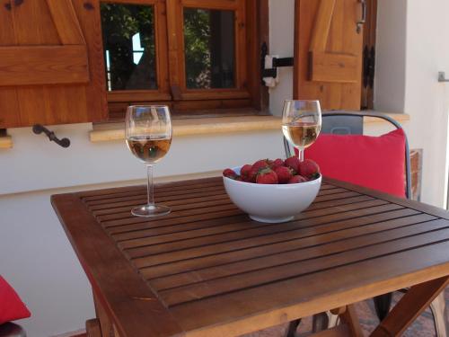 a table with two glasses of wine and a bowl of fruit at Myrtos Bay Apartments in Anomeriá