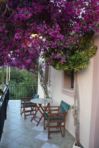 a patio with tables and chairs and purple flowers at Aristotelis Apartments in Frikes