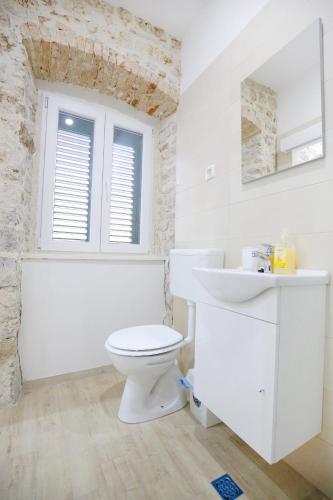 a white bathroom with a toilet and a sink at Apartments Grisogono in Zadar