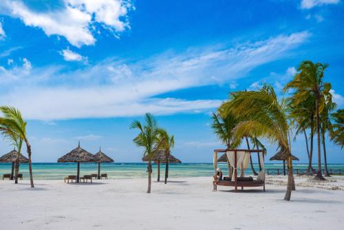a beach with palm trees and a swing at The Sands Beach Resort in Bwejuu