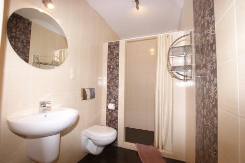 a bathroom with a sink and a toilet and a mirror at Apartamenty przy basenie blisko morza Brown in Puck