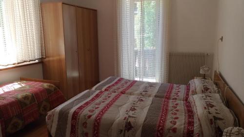 a bedroom with two beds and two windows at Piller Roner Rosa in Sappada