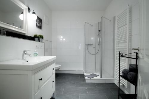 a white bathroom with a sink and a shower at Ferienwohnungen EULE in Lutherstadt Wittenberg